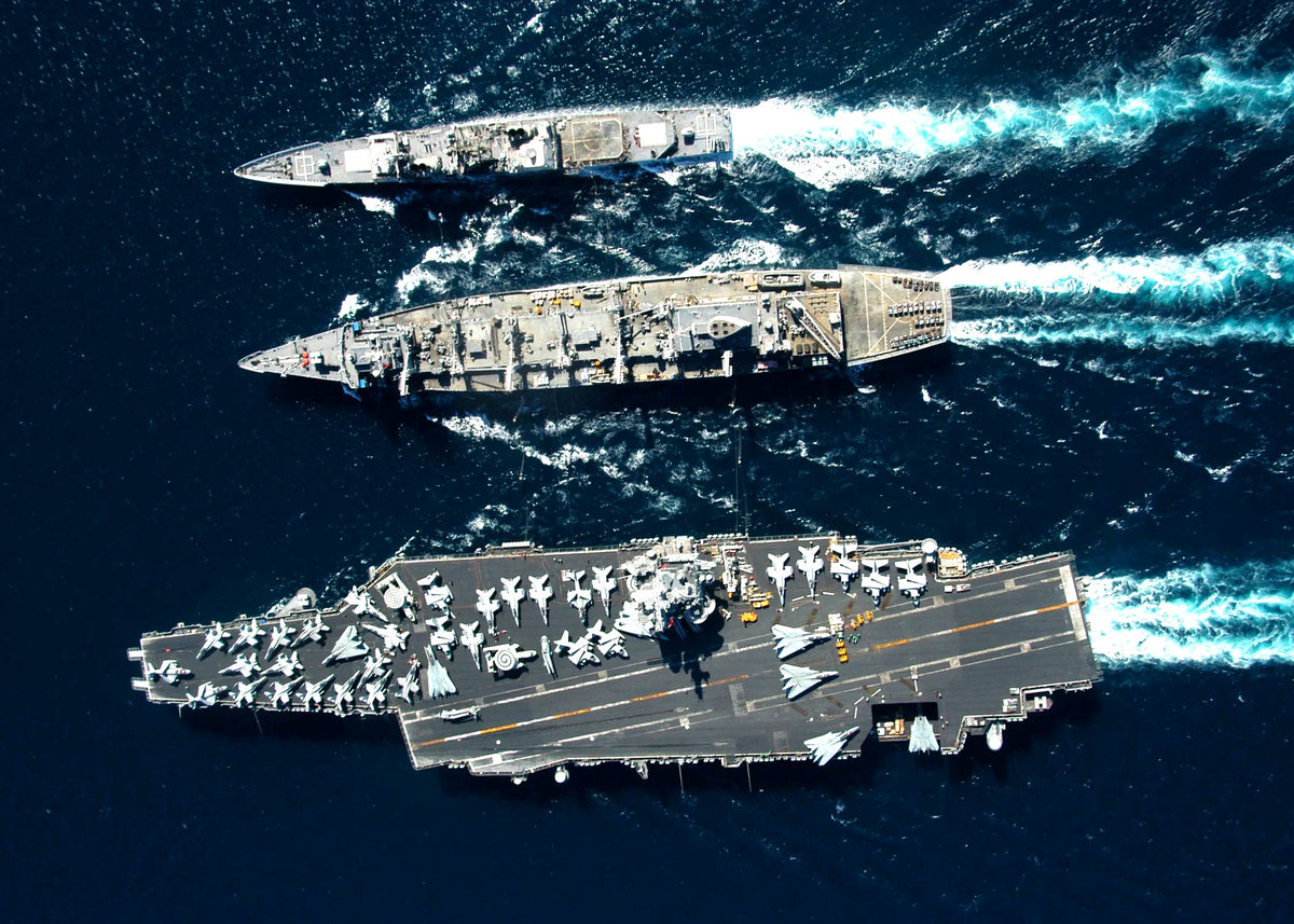 USS Enterprise aircraft carrier underway with a cruiser and supply ship, aerial view, brightened